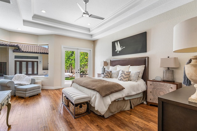 bedroom featuring a raised ceiling, ceiling fan, access to exterior, hardwood / wood-style flooring, and french doors