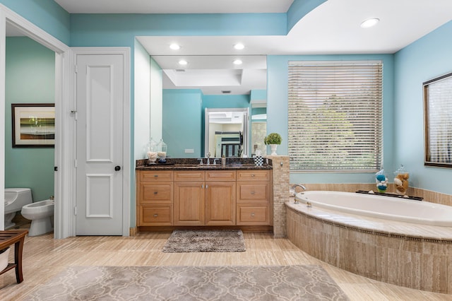 bathroom featuring vanity, tiled bath, a bidet, and toilet