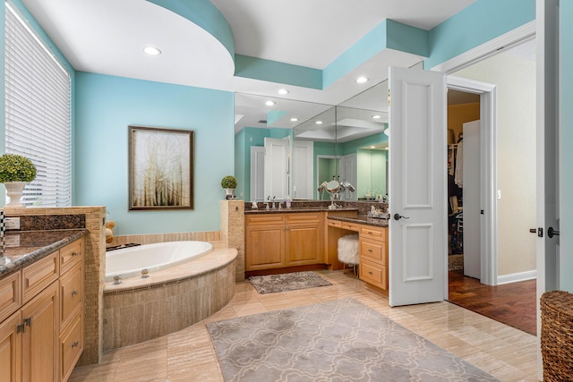 bathroom featuring vanity, hardwood / wood-style floors, and a relaxing tiled tub