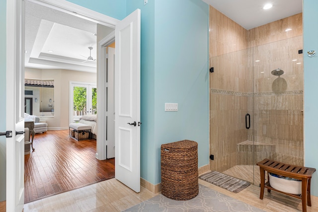 bathroom featuring a shower with door, ceiling fan, a raised ceiling, and hardwood / wood-style floors