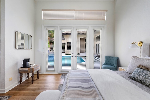 bedroom featuring a towering ceiling, access to outside, french doors, and wood-type flooring