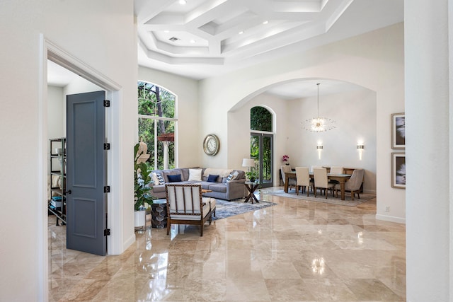 hallway featuring a notable chandelier, coffered ceiling, and a towering ceiling