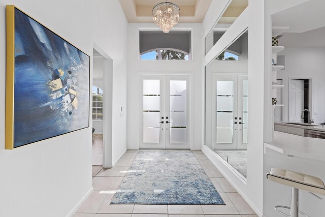 tiled entryway featuring french doors, an inviting chandelier, and sink