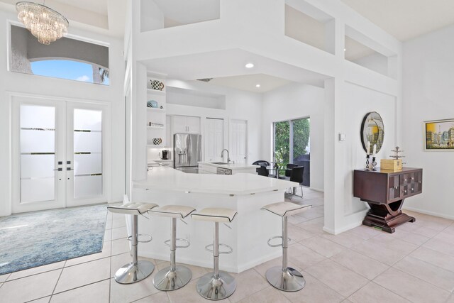 kitchen with white cabinets, hanging light fixtures, sink, stainless steel fridge, and kitchen peninsula