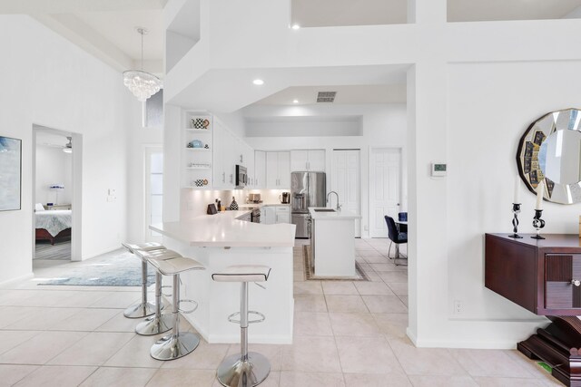 kitchen featuring a kitchen breakfast bar, ceiling fan with notable chandelier, decorative light fixtures, kitchen peninsula, and white cabinetry