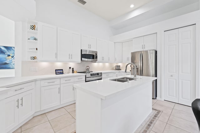 kitchen featuring a center island with sink, appliances with stainless steel finishes, sink, white cabinets, and light tile patterned flooring