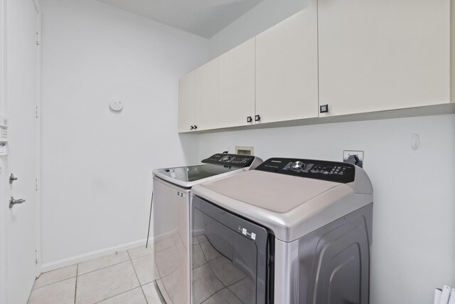 washroom with cabinets, washer and clothes dryer, and light tile patterned floors