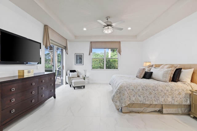 bedroom with multiple windows, ceiling fan, a tray ceiling, and access to outside