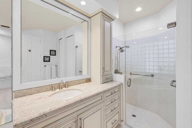 bathroom featuring a shower with door and vanity