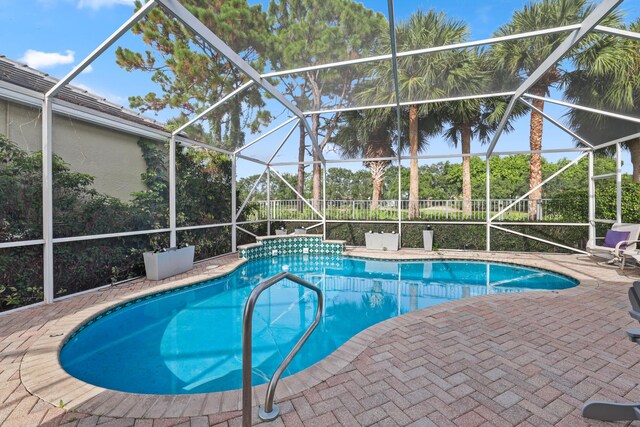 view of swimming pool featuring glass enclosure and a patio