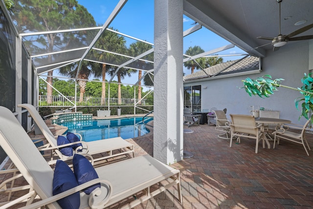 view of pool featuring glass enclosure, ceiling fan, and a patio area