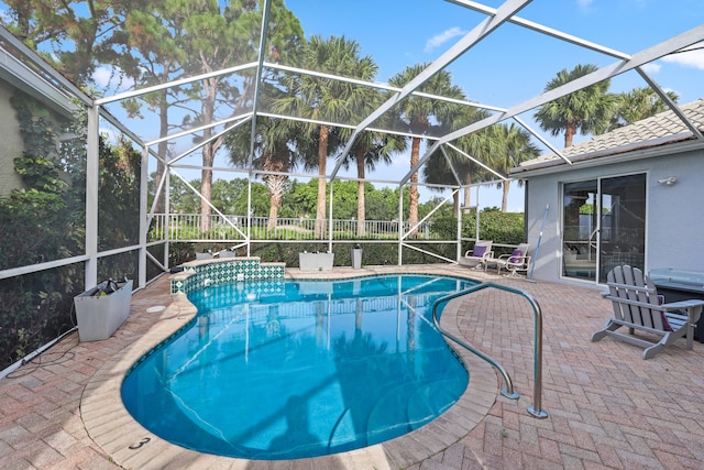 view of pool with a patio area and glass enclosure