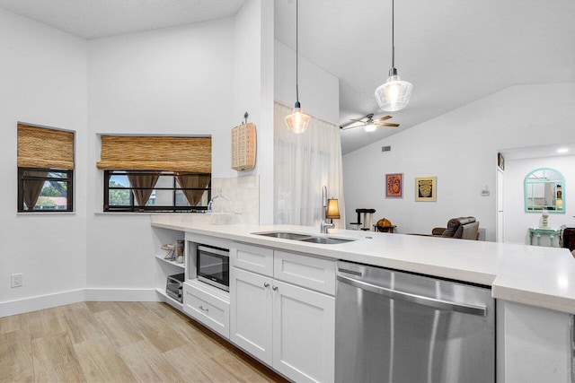 kitchen with white cabinetry, sink, stainless steel appliances, pendant lighting, and lofted ceiling