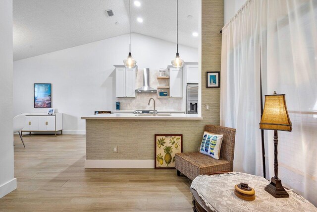 6055 Parkwalk Dr, Boynton Beach, FL 33472 - kitchen featuring wall chimney range hood, light countertops, backsplash, stainless steel fridge, and decorative light fixtures
