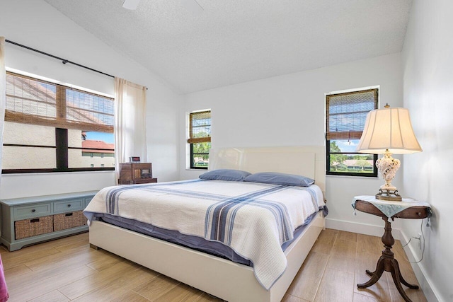 bedroom featuring a textured ceiling, vaulted ceiling, light hardwood / wood-style flooring, and ceiling fan