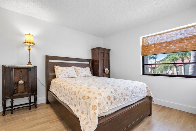 bedroom with a textured ceiling and light wood-type flooring