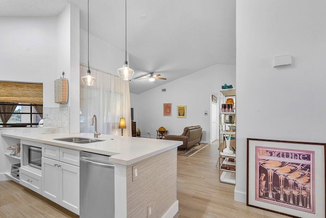 kitchen featuring pendant lighting, dishwasher, sink, vaulted ceiling, and light hardwood / wood-style floors