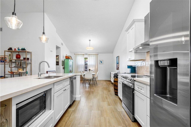 kitchen with sink, decorative light fixtures, lofted ceiling, and appliances with stainless steel finishes