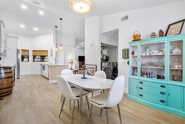 dining area with light hardwood / wood-style floors, sink, and a textured ceiling