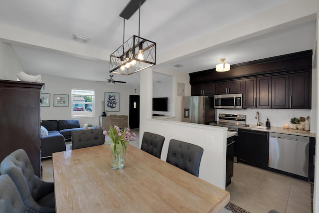 tiled dining area with beam ceiling, ceiling fan with notable chandelier, and sink