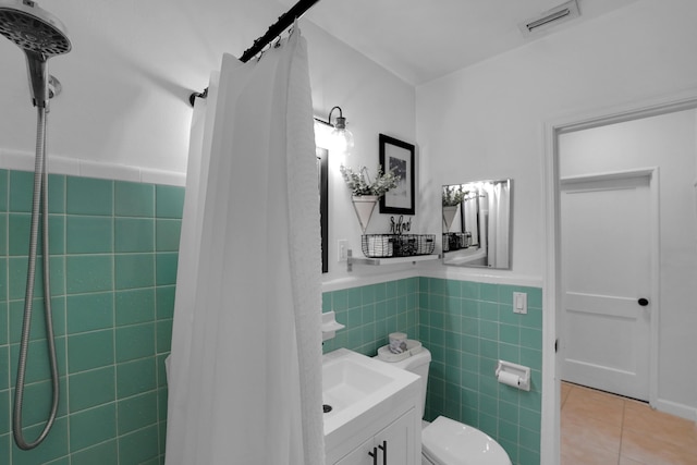 bathroom featuring a shower with shower curtain, tile patterned floors, vanity, tile walls, and toilet