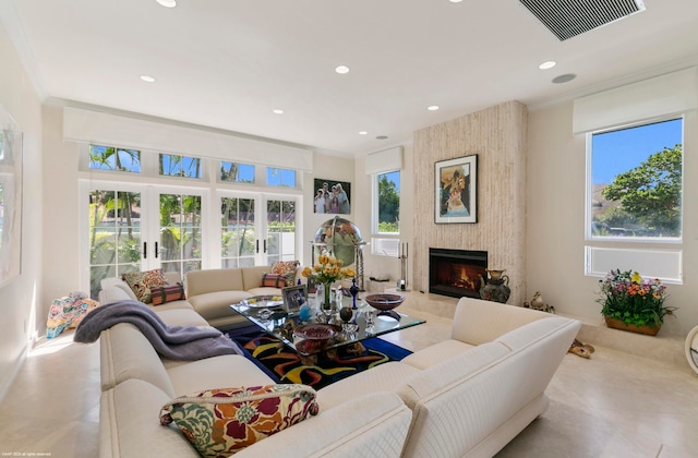 living room featuring a healthy amount of sunlight, tile patterned floors, crown molding, and a large fireplace