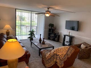 carpeted living room featuring a wealth of natural light and ceiling fan