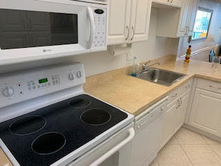 kitchen with white cabinetry, white appliances, and light tile patterned floors