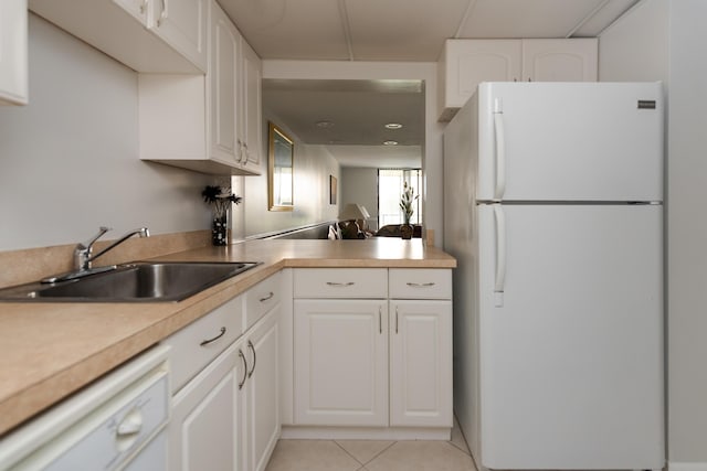 kitchen featuring sink, white appliances, light tile patterned floors, and white cabinets