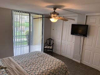 bedroom with dark carpet, access to outside, and ceiling fan