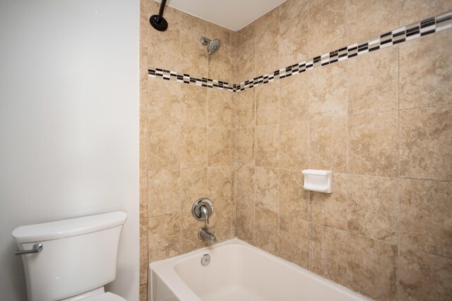 bathroom with toilet and tiled shower / bath combo