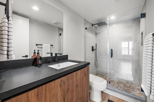 bathroom featuring toilet, vanity, walk in shower, and hardwood / wood-style floors