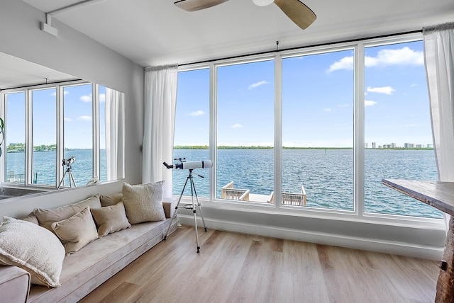 sunroom featuring ceiling fan, a water view, and a healthy amount of sunlight