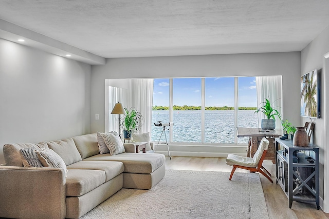 living room with a water view, light wood-type flooring, and a textured ceiling