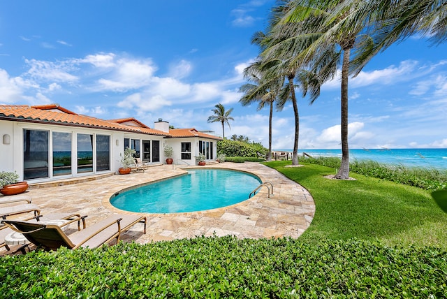 view of pool featuring a yard, a water view, and a patio area