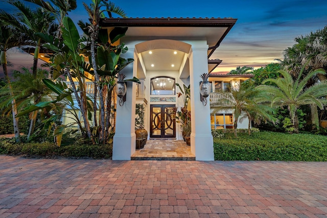 exterior entry at dusk with a balcony and french doors