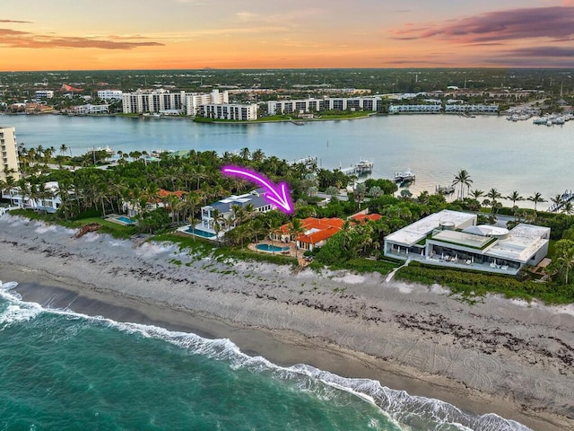 aerial view at dusk featuring a view of the beach and a water view