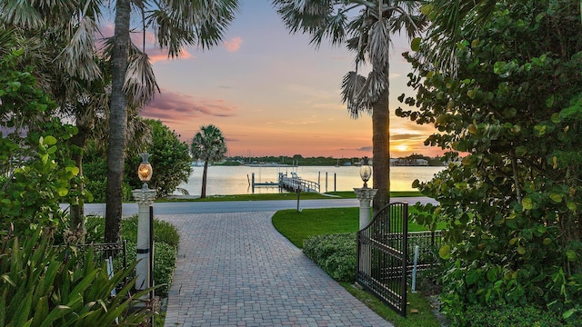 view of home's community featuring a boat dock, a lawn, and a water view