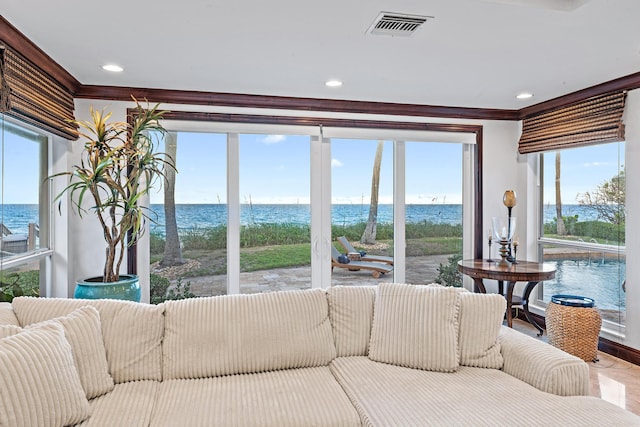 living room featuring a healthy amount of sunlight, a water view, and ornamental molding