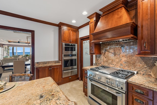 kitchen featuring stainless steel appliances, light stone counters, custom range hood, decorative backsplash, and crown molding