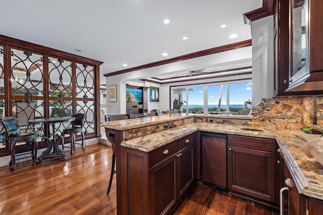 kitchen with ceiling fan, dark hardwood / wood-style flooring, a breakfast bar area, and kitchen peninsula