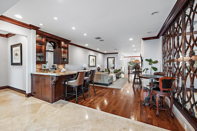 bar with ornamental molding and hardwood / wood-style floors