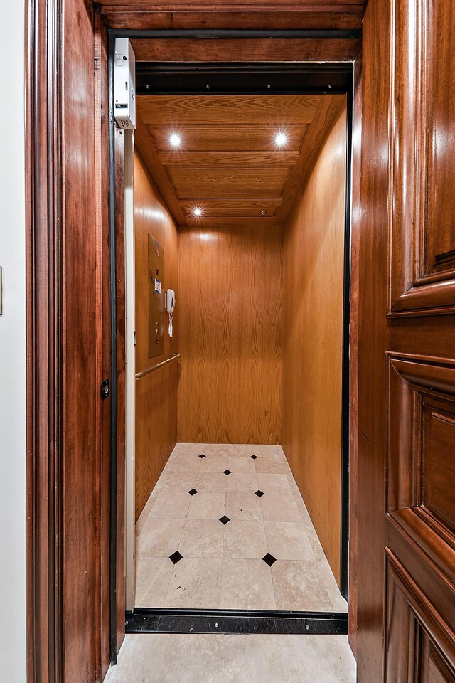 interior details featuring wooden walls, wooden ceiling, and elevator