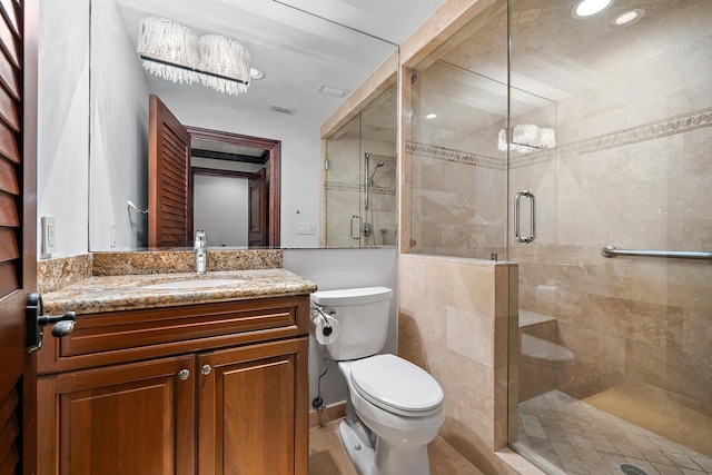 bathroom with vanity, toilet, a chandelier, and a shower with shower door