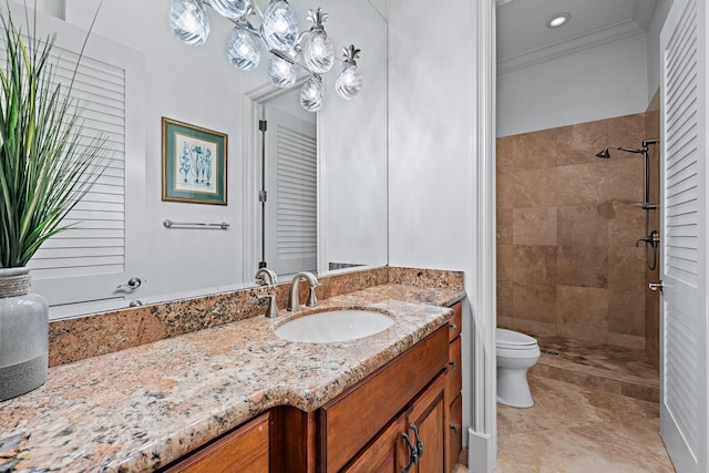 bathroom with tiled shower, crown molding, vanity, and toilet