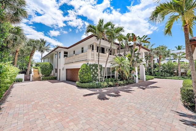 view of front of property with a balcony, a tile roof, decorative driveway, and stucco siding