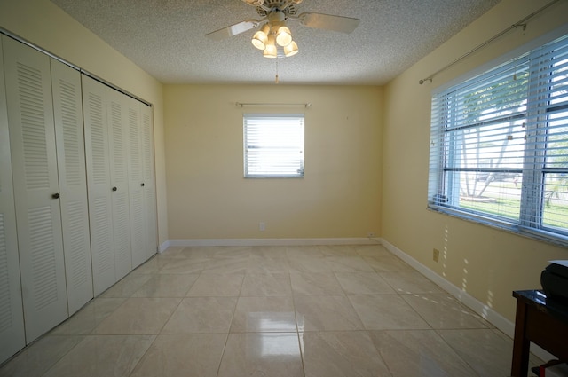 bedroom featuring light tile patterned floors, a textured ceiling, and ceiling fan