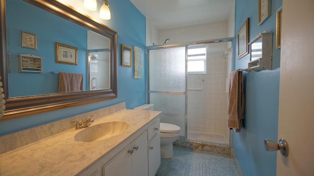 bathroom featuring tile patterned flooring, vanity, a shower with shower door, and toilet