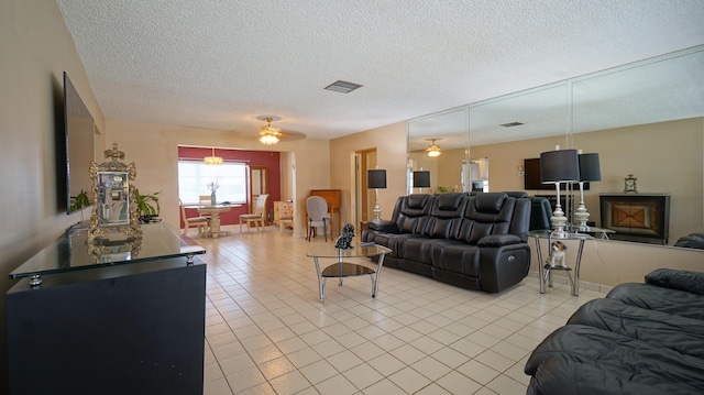 living room with ceiling fan, light tile patterned floors, and a textured ceiling