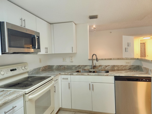 kitchen with white cabinetry, a textured ceiling, stainless steel appliances, sink, and light stone countertops